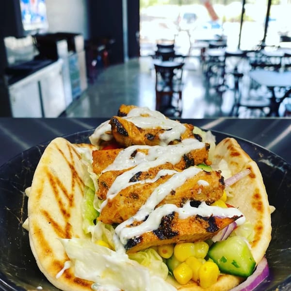 Grilled chicken pita with lettuce, corn, cucumber, red onion, and white sauce at Bowls N Go.