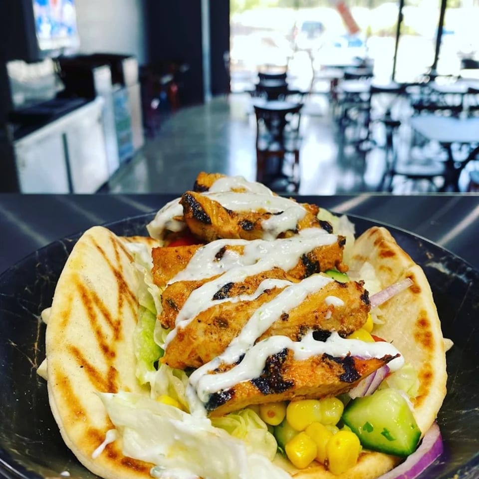 Grilled chicken pita with lettuce, corn, cucumber, red onion, and white sauce at Bowls N Go.